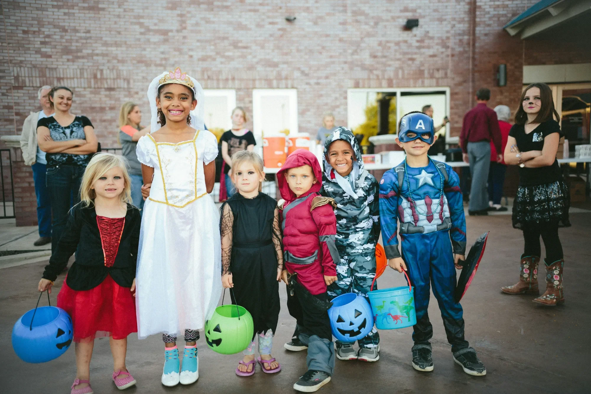 Respekt, Ehrlichkeit und Empathie: Die wichtigsten Werte für Kinder Sechs Kinder in Kostümen halten Halloween-Eimer auf einer Feier.