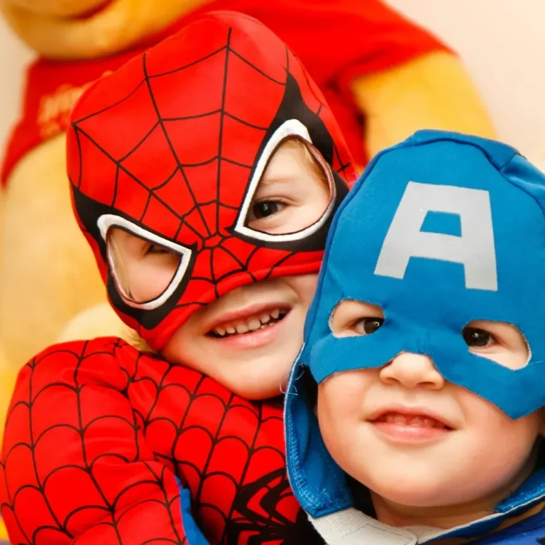 Kostenloser-Miniguide-Kinder-Spielerisch-Werte-Vermitteln Zwei Kinder in Superheldenkostümen, eines als Spiderman, das andere als Captain America.